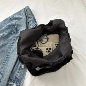 Schwarze Plüsch-Tragetasche mit großem Fassungsvermögen und Alltagsutensilien auf Denim
