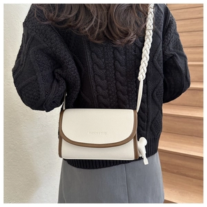 Chic beige crossbody bag with contrast brown trim and wide woven strap on a model