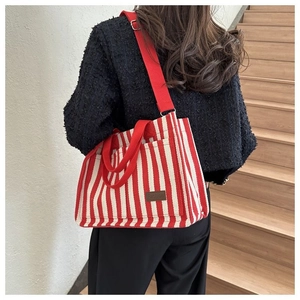 Détail du sac cabas en toile à rayures rouges avec bandoulière large et étiquette en cuir