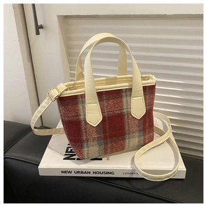 Dettaglio mini borsa in tweed a quadri bianchi e rossi appoggiata su un libro urbano