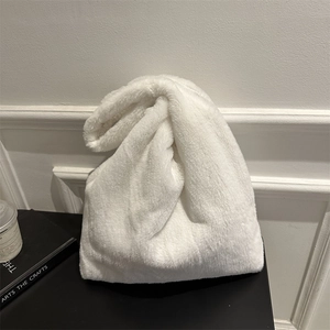 Minimalistische weiße Plüsch-Tragetasche mit Knotengriff vor schlichtem weißem Hintergrund