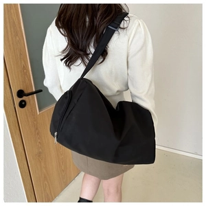 Détail du sac bandoulière en nylon noir avec sangle réglable et poche zippée latérale