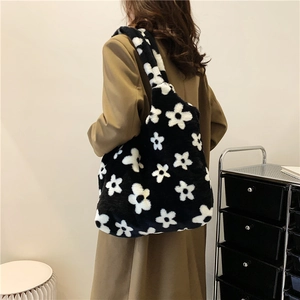 Fashionable black and white floral plush tote bag shown on model with camel coat