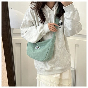 Detail of mint green corduroy crescent bag with cartoon bear embroidery and zip closure