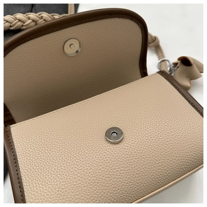 Macro detail of beige pebble leather crossbody bag with magnetic buckle and brown trim