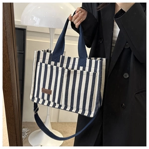 Détail du sac cabas en toile rayé bleu et blanc avec étiquette en cuir et poignée solide