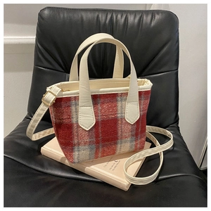 Dettaglio borsa a tracolla in tela a scacchi rossi e beige con tracolla color crema regolabile