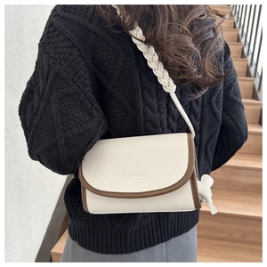 Detail of crossbody bag with woven rope strap and bow decoration on cream leather