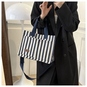 Détail du sac cabas en toile à rayures bleu marine montrant le patch et les anses