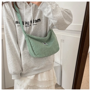 Detail of light green corduroy crescent bag with cartoon bear patch and soft texture