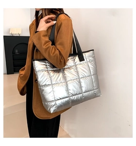 Detalle del bolso tote plateado acolchado grande con textura de tejido metálico brillante