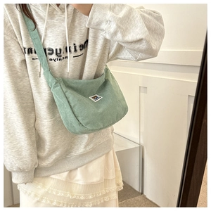 Detail of mint green corduroy crossbody bag featuring a cute bear patch and soft texture