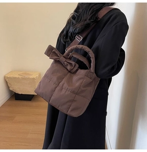Sac à main matelassé marron avec nœud porté par un mannequin en manteau long