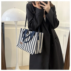 Reflet miroir d'un sac cabas en toile rayée avec étiquette en cuir marron et bandoulières