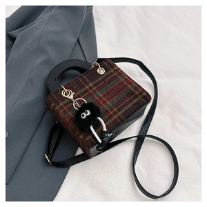 Detail of plaid wool handbag with green and brown checks and black leather handle
