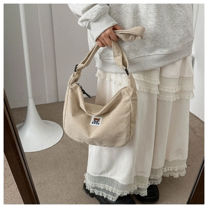 Detail view of corduroy crescent crossbody bag with cute bear patch and wide strap