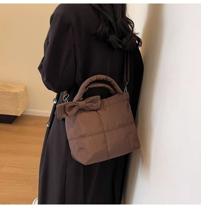 Sac fourre-tout matelassé marron avec nœud, porté par un mannequin dans un intérieur