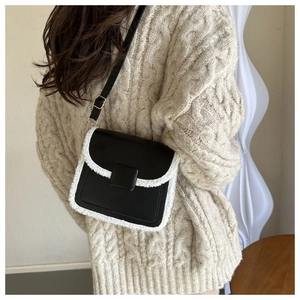 Detail of color-contrast crossbody bag with plush trim on a model in a cable knit sweater