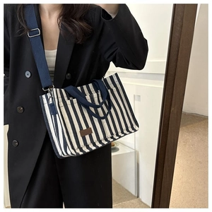 Selfie miroir montrant le sac cabas en toile à rayures bleues et blanches et logo en cuir