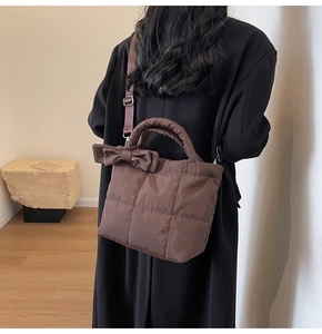 Détail du sac cabas matelassé marron foncé avec nœud porté à l'épaule par un mannequin