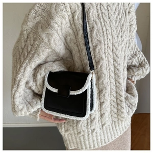 Detail of crossbody bag featuring contrast faux shearling trim and black leather flap