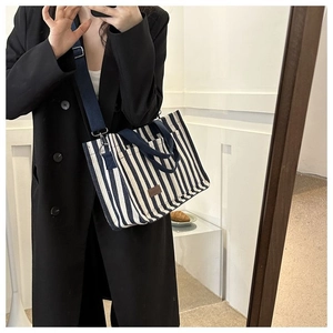 Vue détaillée du sac cabas en toile rayée bleue avec patch logo en cuir marron chic