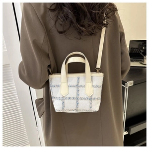 Dettaglio di una borsa a tracolla in tweed a quadri con manici bianchi su una modella