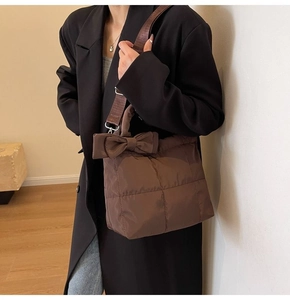Détail d'un sac matelassé marron avec un grand nœud décoratif sur le côté latéral
