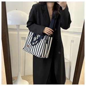 Détail du sac cabas en toile rayé bleu et blanc avec étiquette en cuir et bandoulière