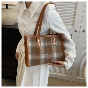 Detailed view of brown plaid tweed tote bag with leather straps and gold metal rivets