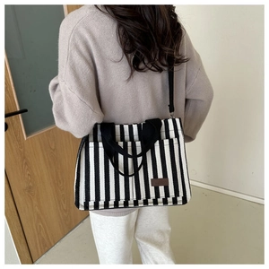 Détail du sac cabas en toile à rayures noires et blanches avec étiquette en cuir brun