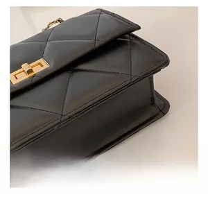 Détail de surpiqûres en losange et fermoir doré sur le petit sac carré noir à bandoulière
