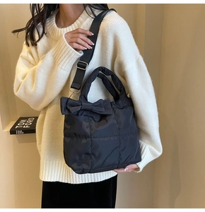 Détail d'un sac cabas en nylon matelassé noir avec un grand nœud et une bandoulière large