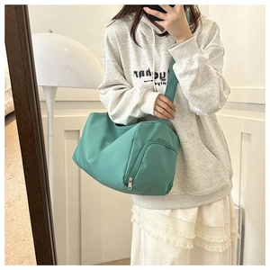 Detail of mint green nylon shoulder bag showing the side zipper pocket and texture