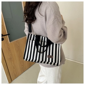Détail du sac cabas en toile rayée avec étiquette en cuir et bandoulière noire