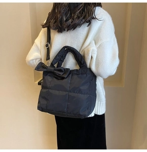 Gros plan du sac fourre-tout matelassé avec nœud porté par un mannequin en extérieur
