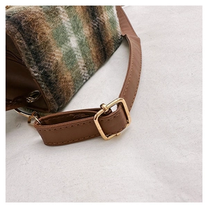 Detail of green plaid wool fabric and brown leather strap with golden metal buckle