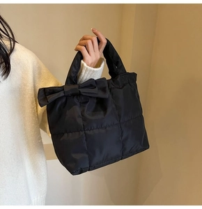 Détail du sac cabas matelassé noir avec nœud décoratif et poignée rembourrée