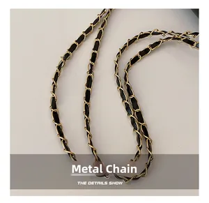 Détail d'une chaîne en métal doré entrelacée d'un bracelet en cuir noir pour sac à main