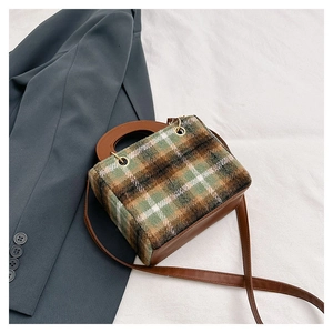 Flat lay of a plaid wool crossbody bag with brown leather details on white fabric