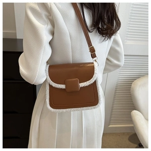 Detail of a brown leather and white shearling crossbody bag on a female model