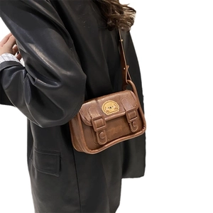 Sac à bandoulière vintage marron avec écusson chiot et boucles porté par un mannequin
