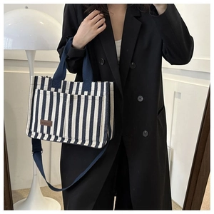 Détail du sac fourre-tout en toile à rayures bleues avec poches avant et étiquette cuir