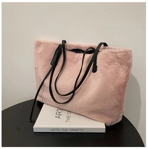 Dettaglio della borsa tote in pelliccia sintetica rosa con manici in pelle nera su libri