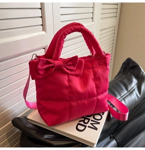 Détail d'un sac à main matelassé magenta avec un grand nœud et une bandoulière large