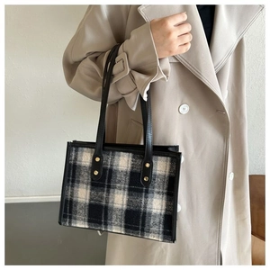 Detailed view of checkered wool tote bag with black leather handles and gold studs