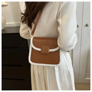 Detail of brown and white crossbody bag with plush faux fur trim on white dress