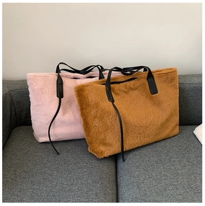 Détail de grands sacs cabas en peluche rose et marron avec anses en cuir sur un canapé
