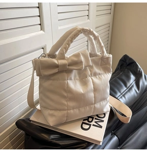 Détail d'un sac matelassé beige crème avec un grand nœud décoratif et texture douce