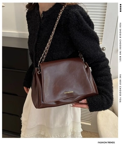 Detail of dark brown leather tote with chain strap and gold embossed fashion lettering